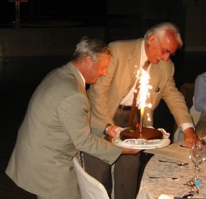 Milan Dimitrijevic and Helmut Kern holding cake with flaming candles